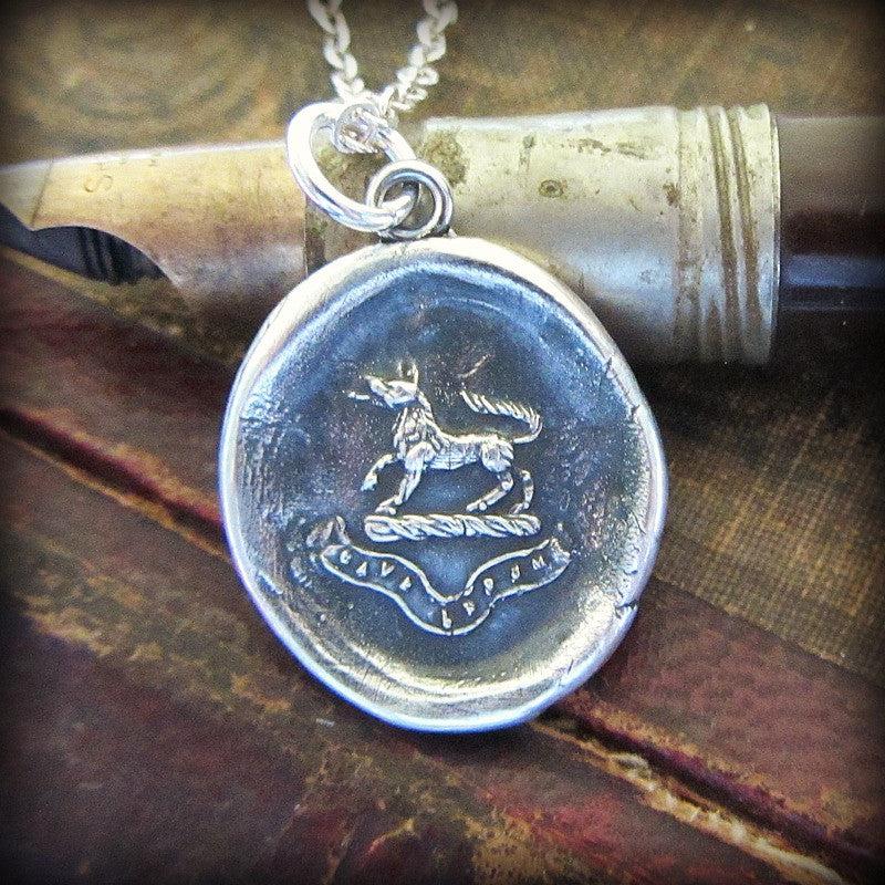 Wolf Wax Seal Pendant Necklace over a pen