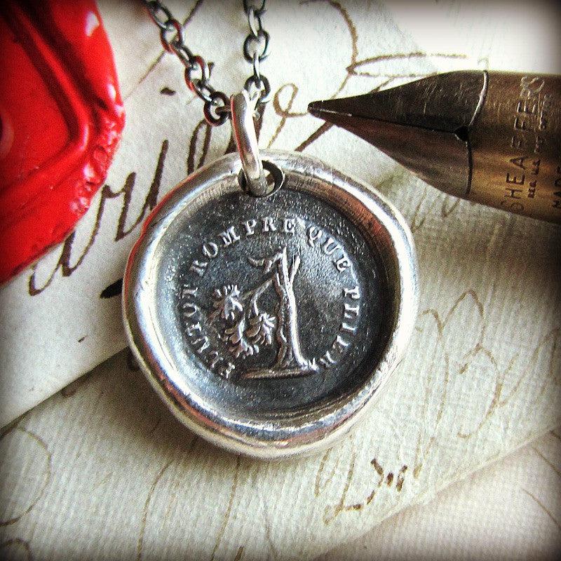 Broken tree wax seal necklace next to pen