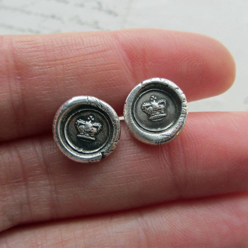 Tiny Crown Wax Seal Earrings in a hand