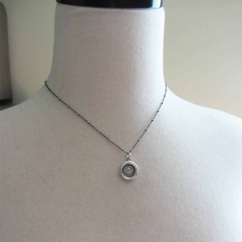 flower forget me not wax seal necklace on a mannequin