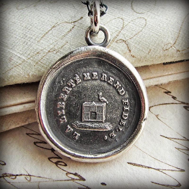 bird out of its cage wax seal necklace close up