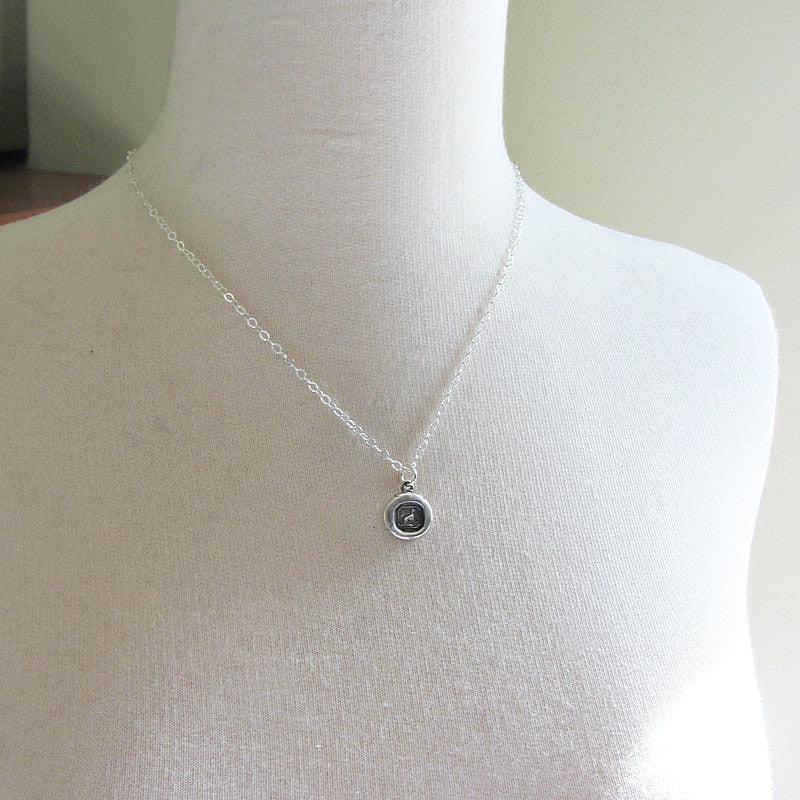 Tiny Greyhound Wax Seal Charm on a mannequin