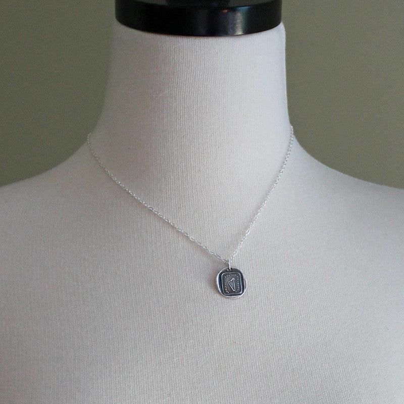 harp wax seal necklace on a mannequin