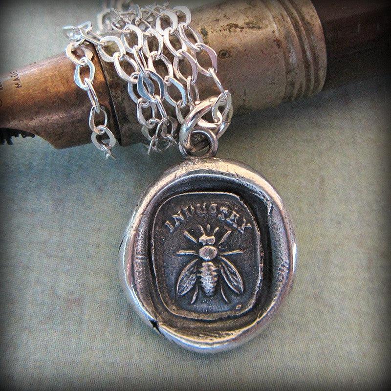 Large bee wax seal necklace wrapped around a pen