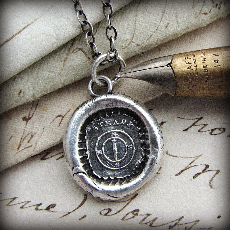 Large compass wax seal necklace next to a pen