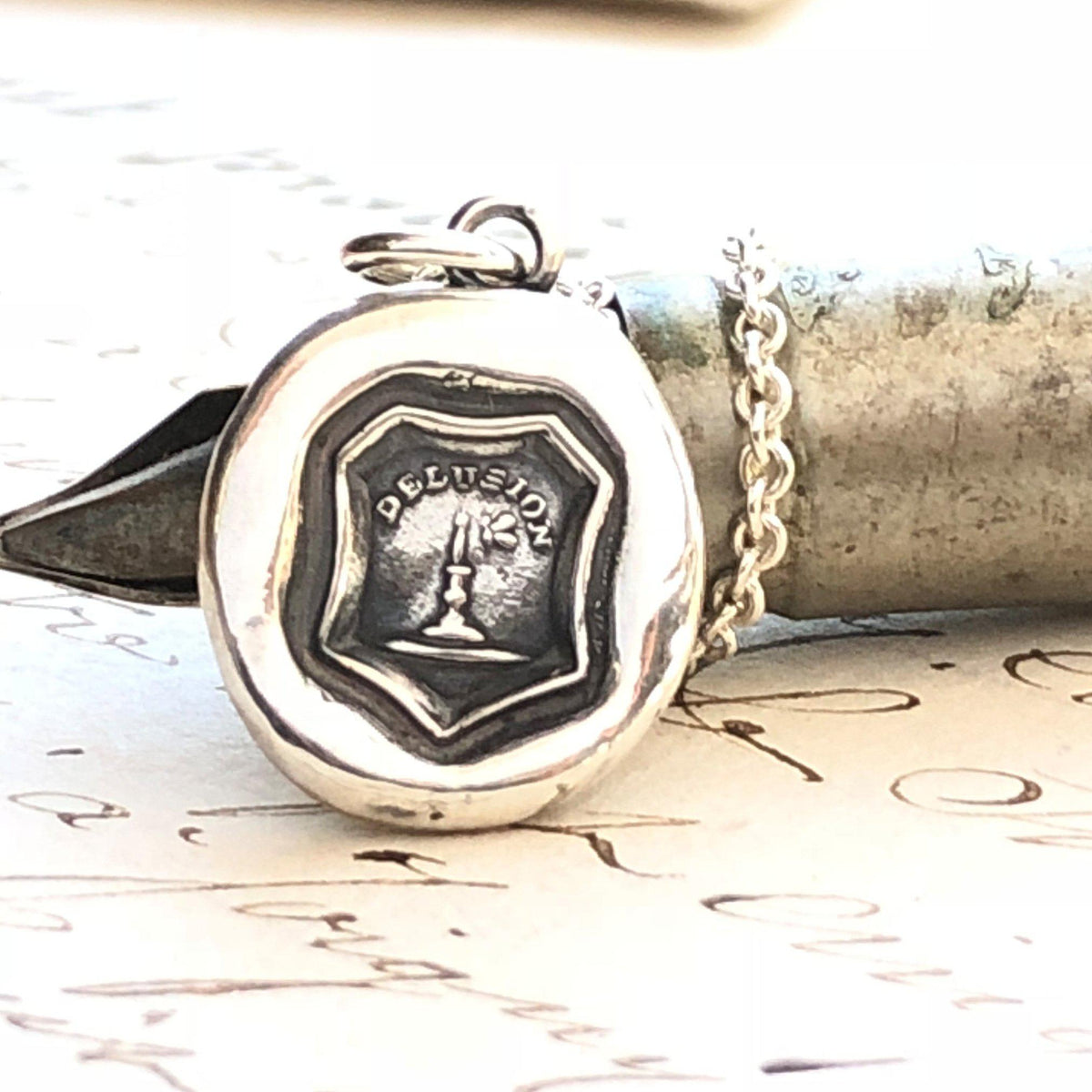 Delusion wax seal necklace over a pen