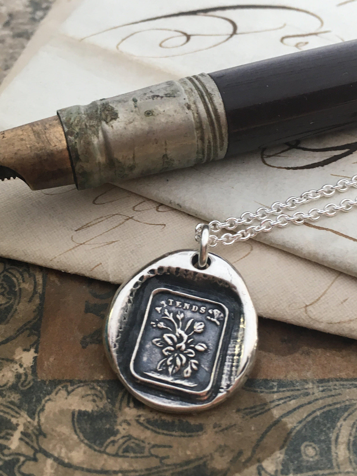foliage wax seal necklace next to a pen