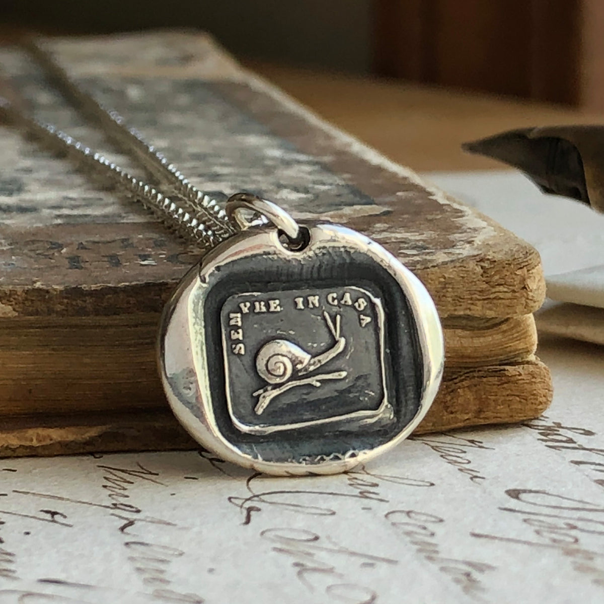 Snail wax seal necklace on a book