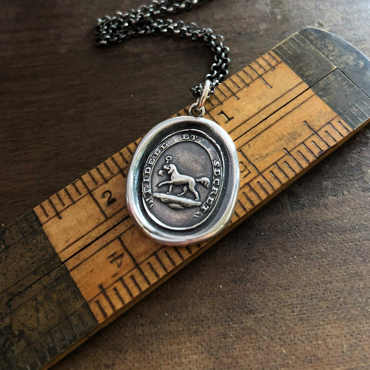Friendship dog wax seal necklace on a ruler