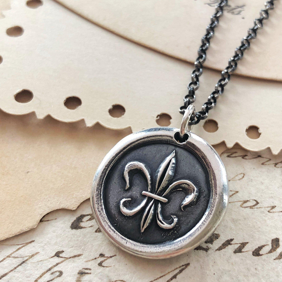 Fleur wax seal close up with a dark chain