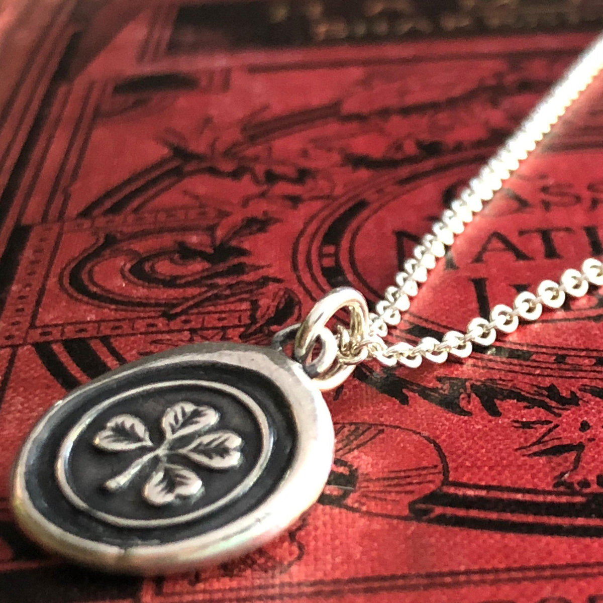 clover wax seal necklace on a book