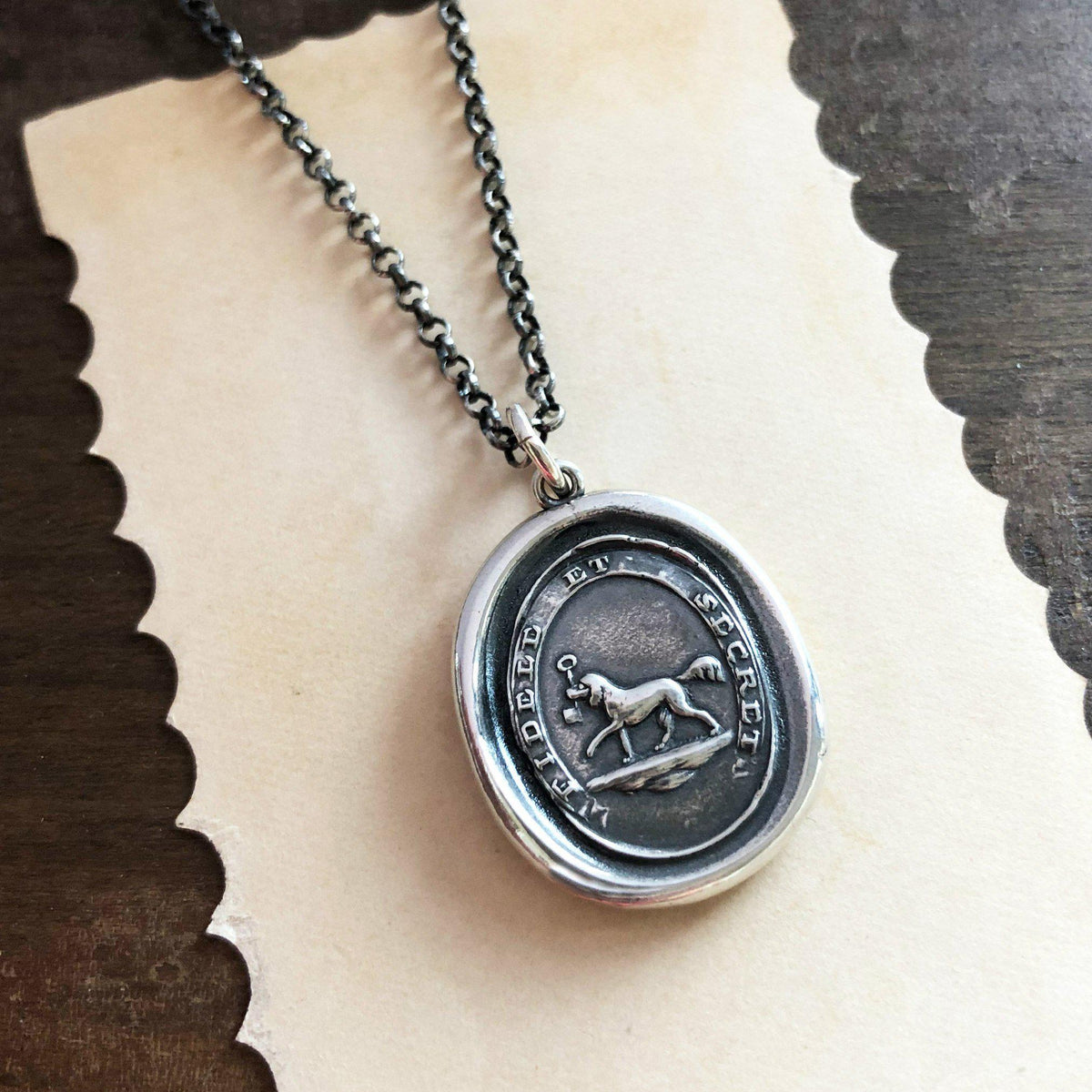 Friendship dog wax seal necklace on a piece of paper