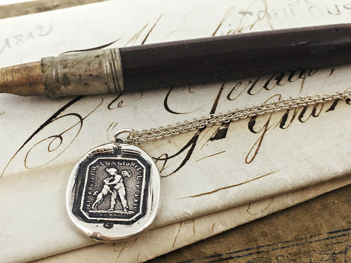 Friendship wax seal necklace next to a pen