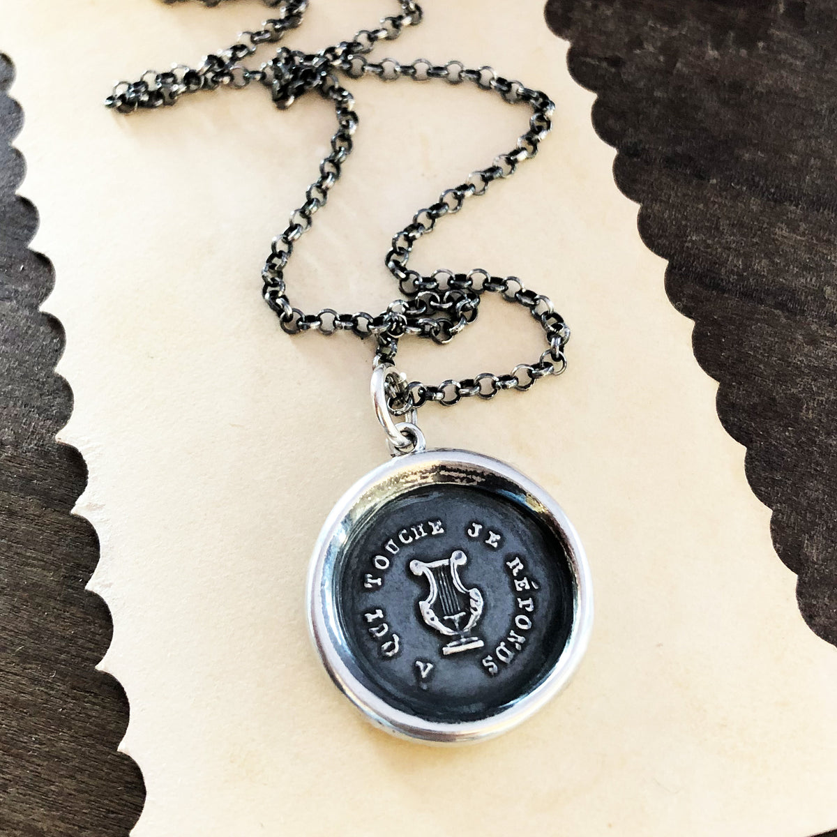 Harp wax seal necklace on piece of paper