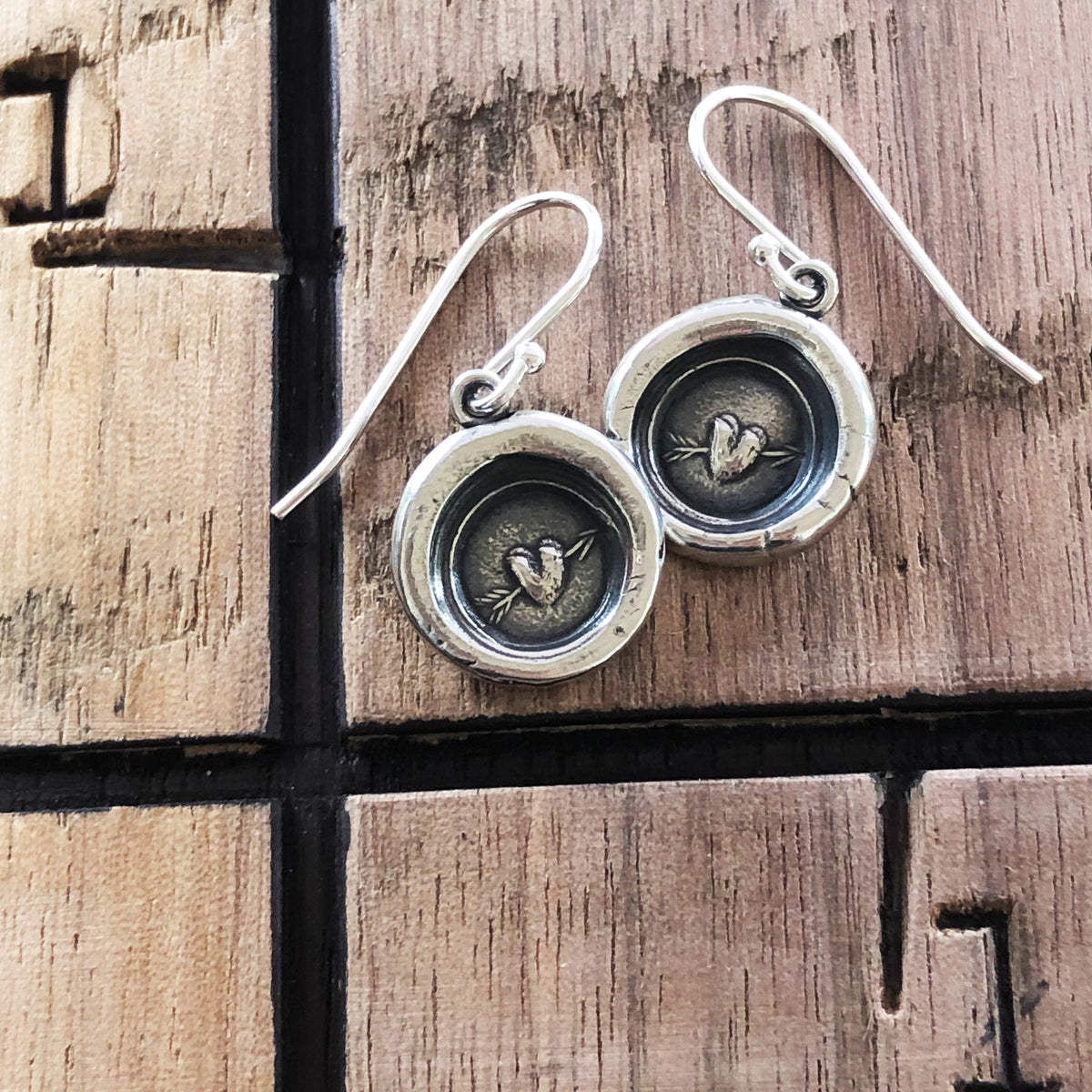 Arrow and hear wax seal earrings on wood