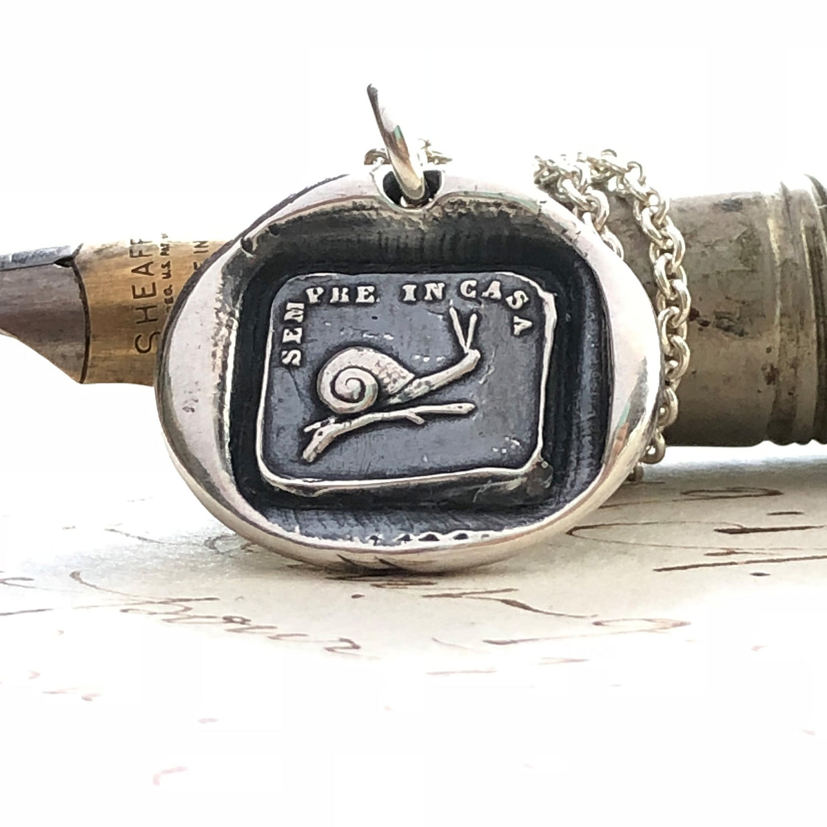 Snail wax seal necklace on a pen