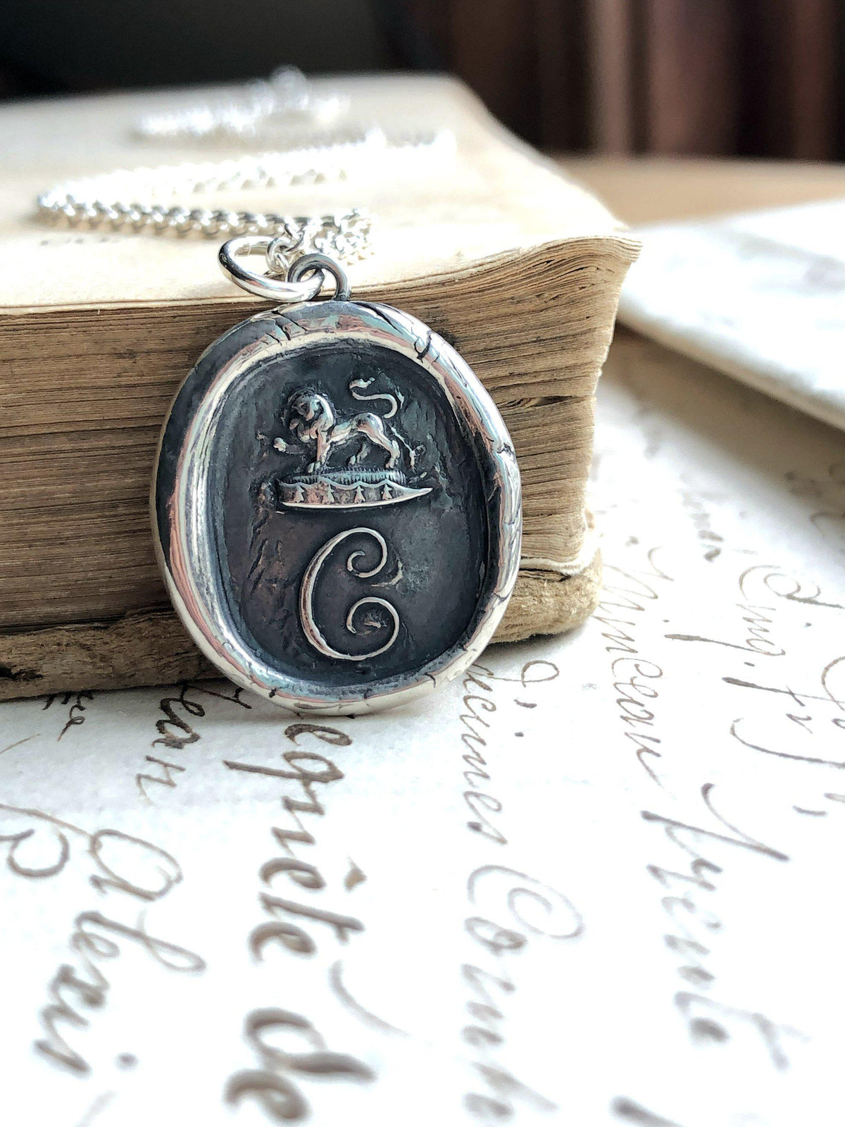 Initial wax seal necklace in front of a book