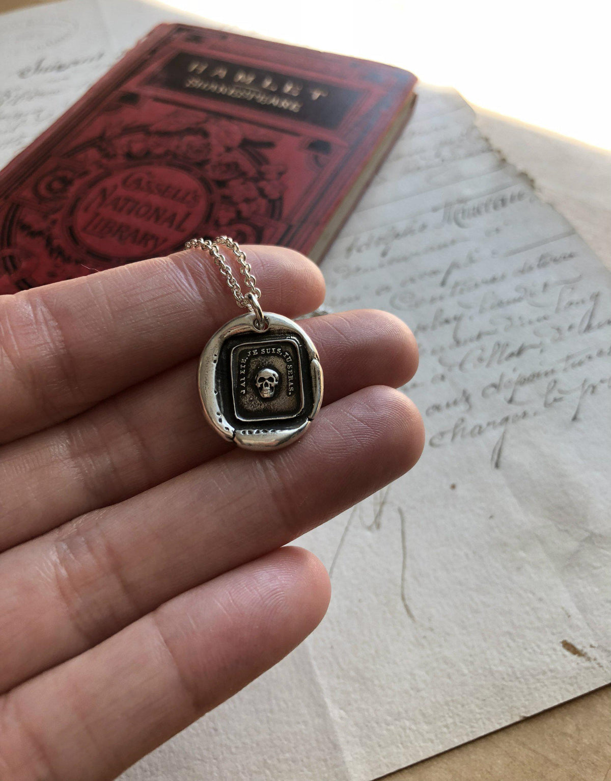 momento skull wax seal necklace in a hand