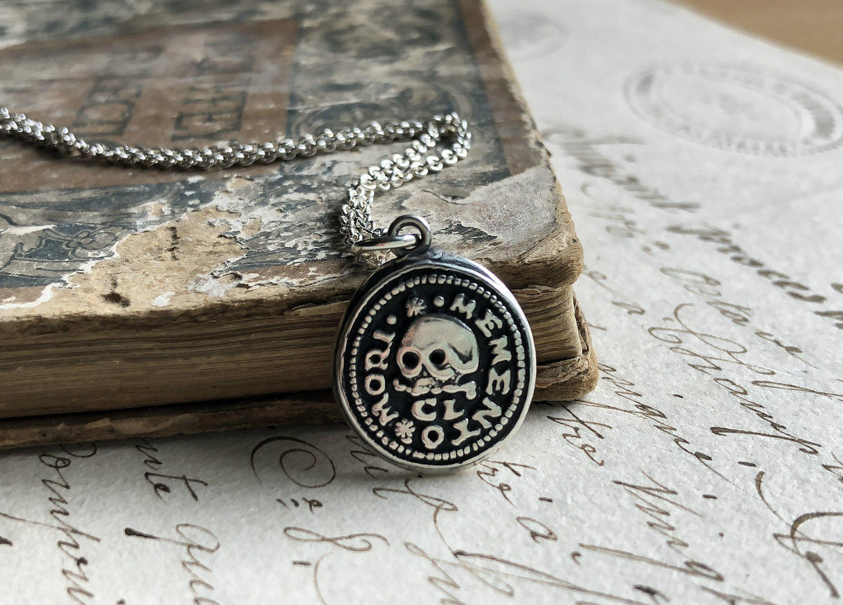 Skull on this wax seal necklace on a book
