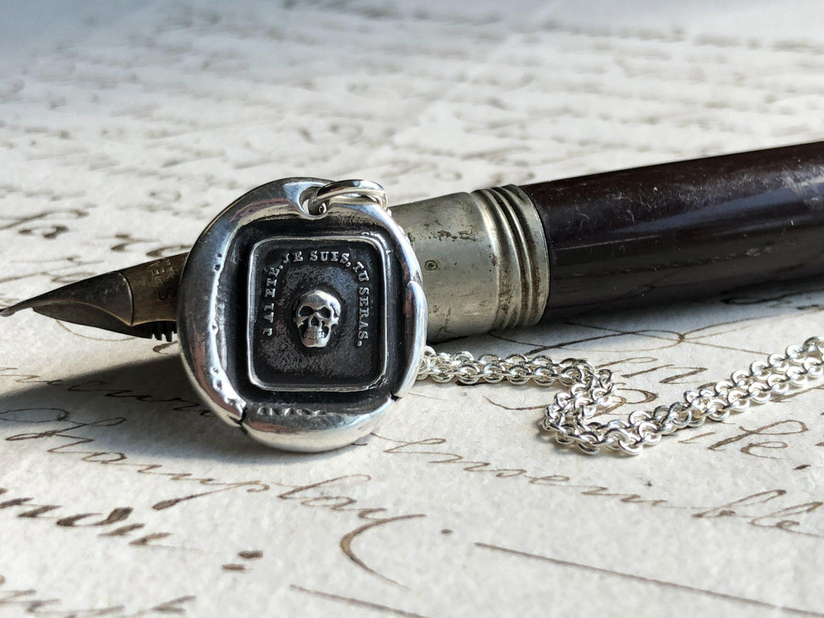 momento skull wax seal necklace over a pen