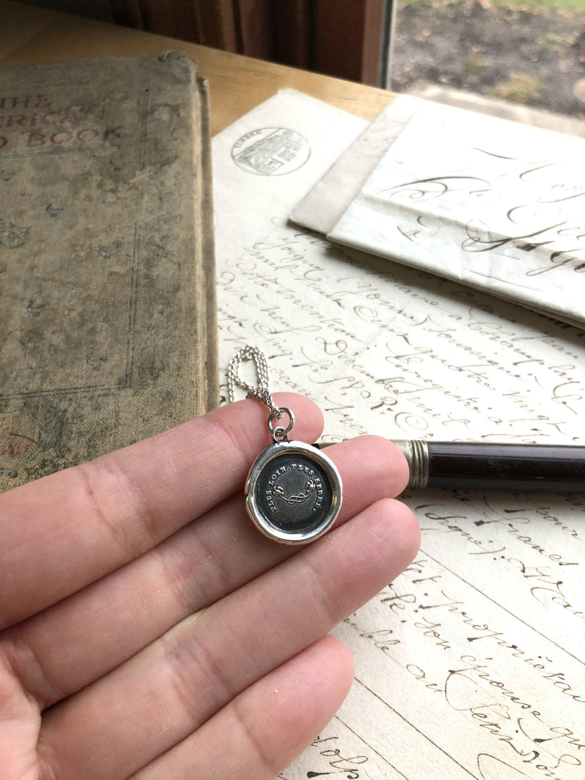 Mothers knot wax seal necklace in a hand