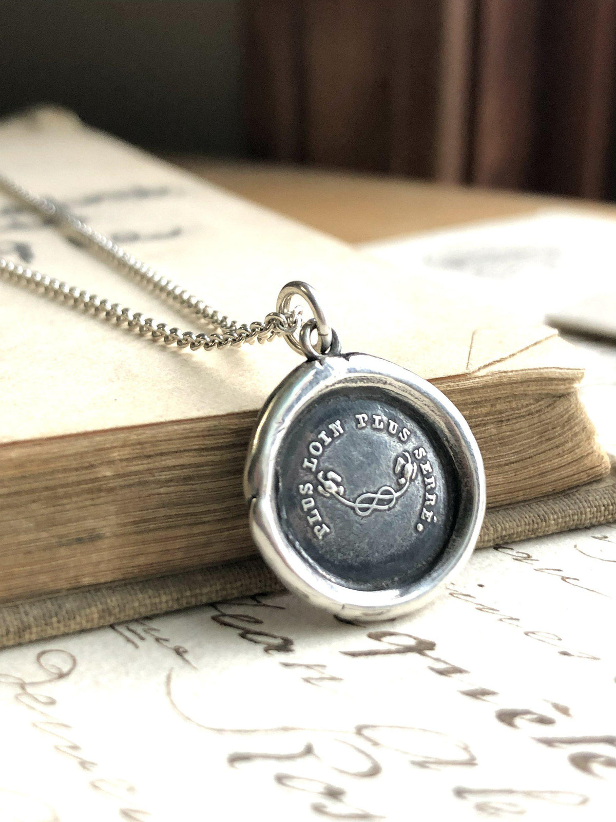Mothers knot wax seal necklace over a book