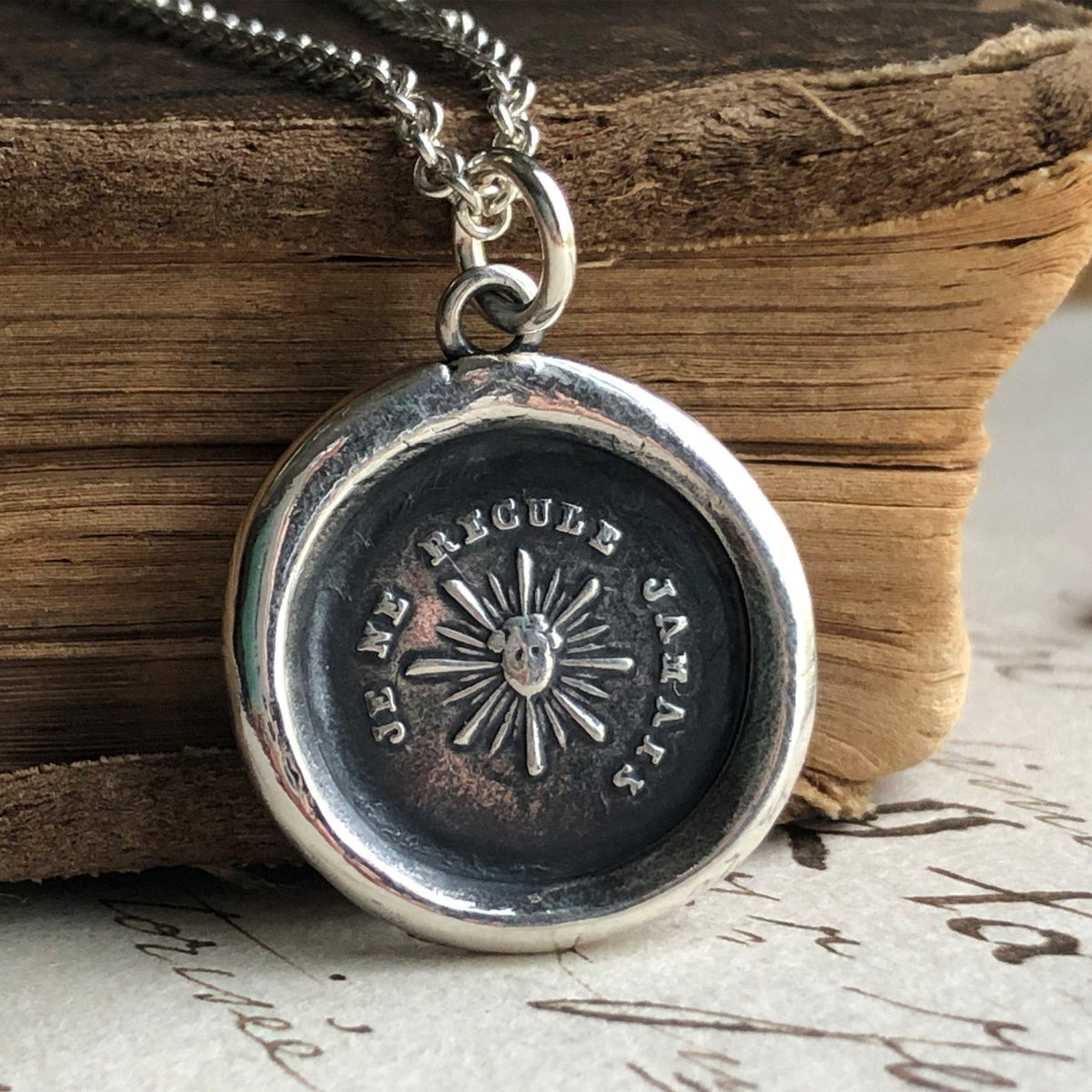 Never back down wax seal necklace laying over a book