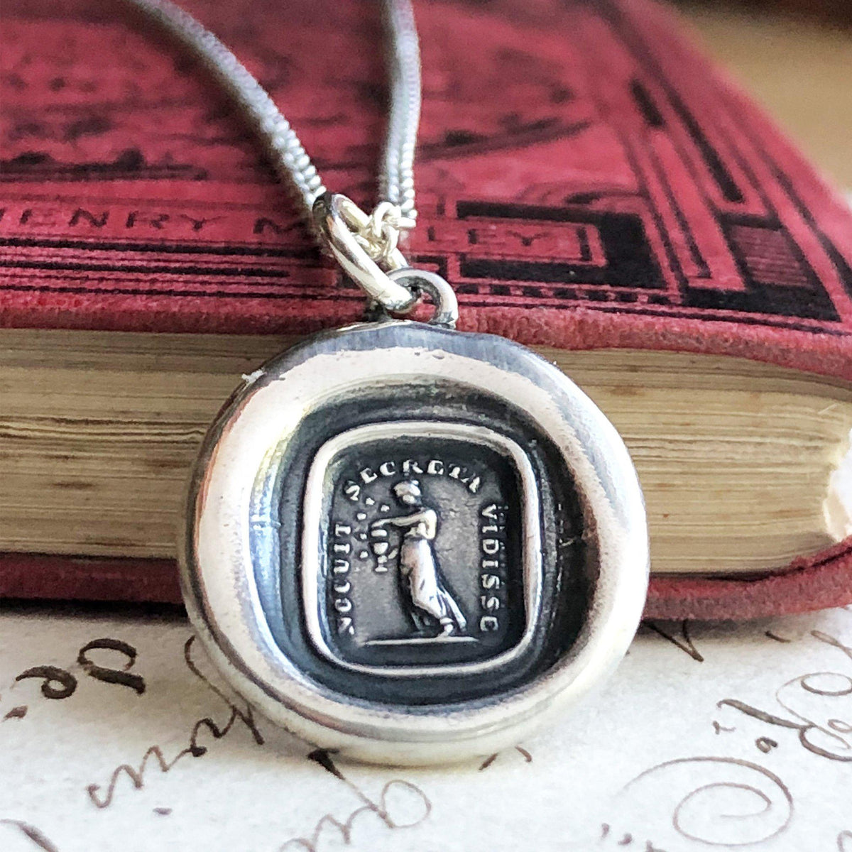 Pandora box wax seal necklace on a book