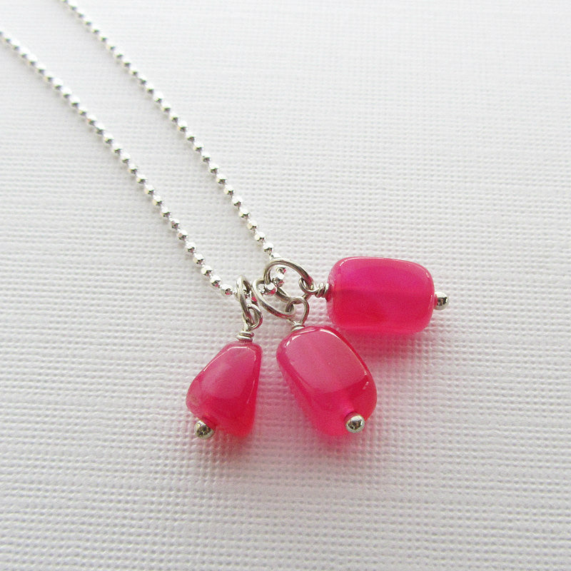 Three hot pink chalcedony nugget charms.