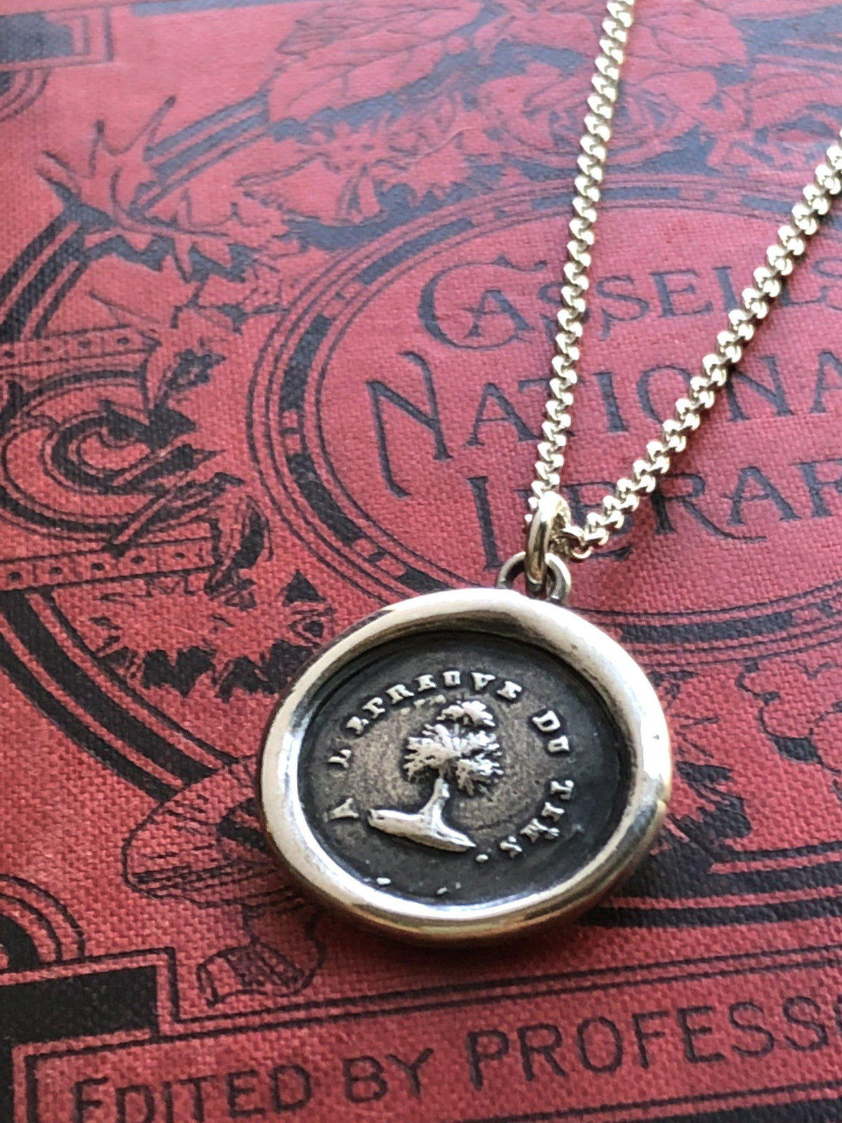 Steadfast tree wax seal necklace on a red book