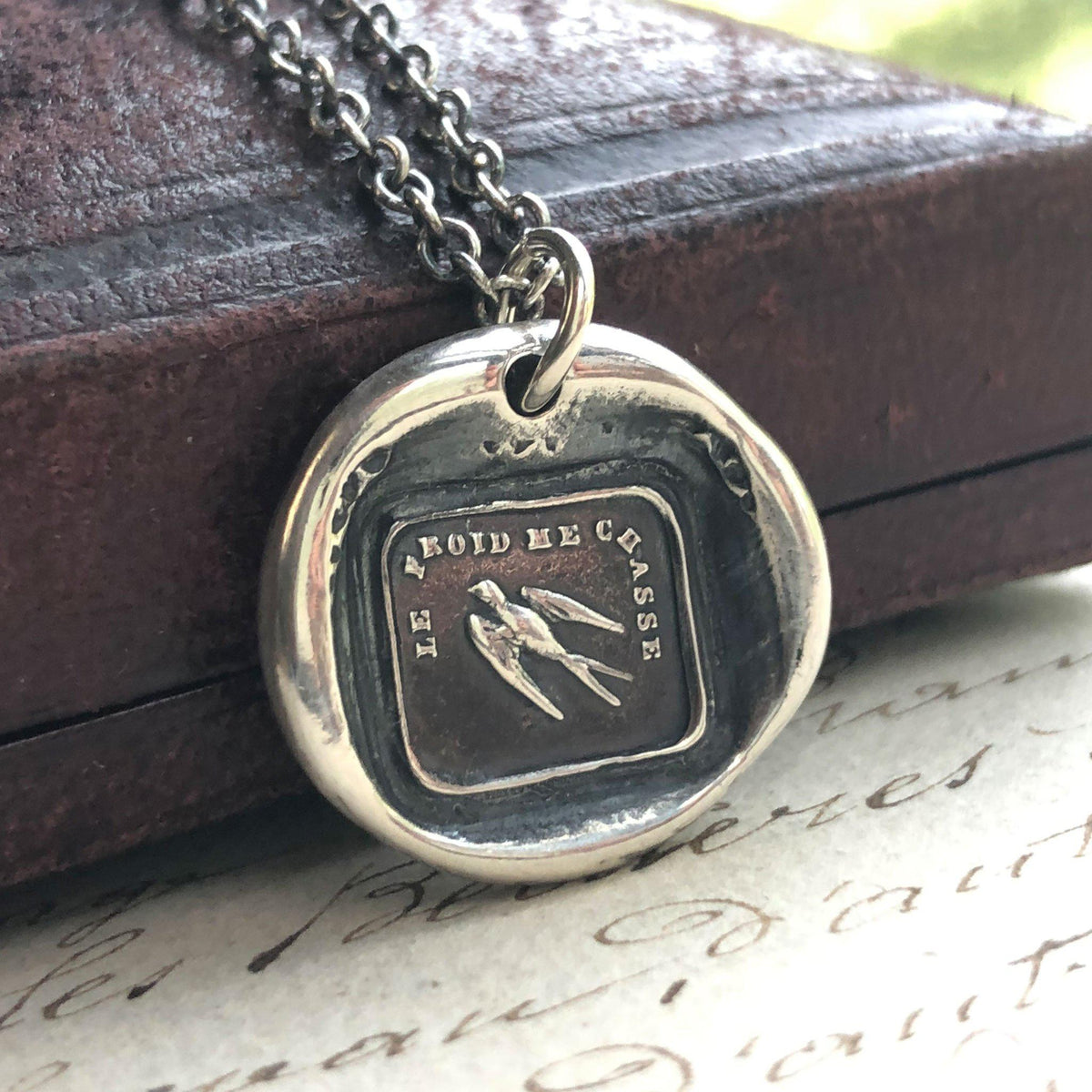 Swallow wax seal necklace on a book