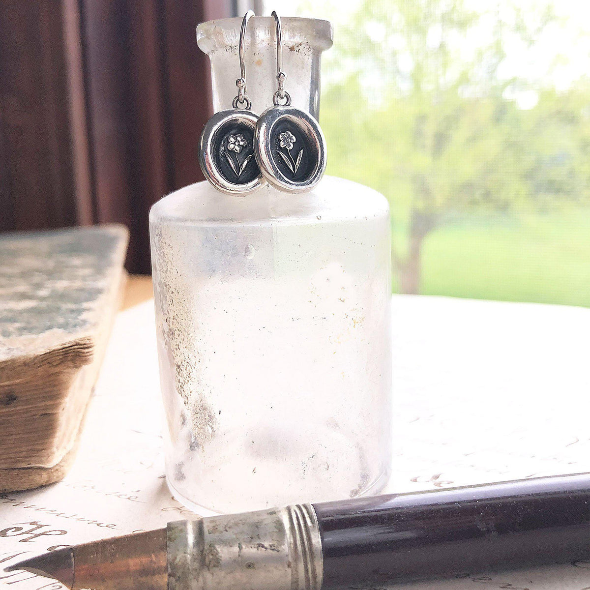 Tiny flower wax seal earrings on jar